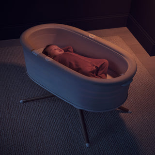 Baby sleeping in a elvie rise in a dimly lit room