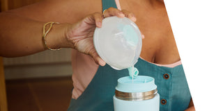 Person pouring a breast milk from a Elvie Wave container into a teal Elvie breast milk cooler.