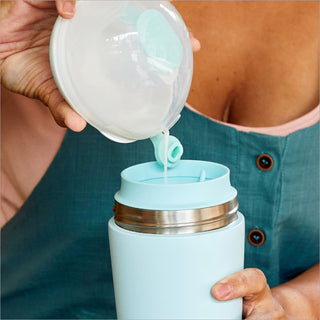 Person pouring breast milk from Elvie Wave into a teal Elvie breast milk cooler