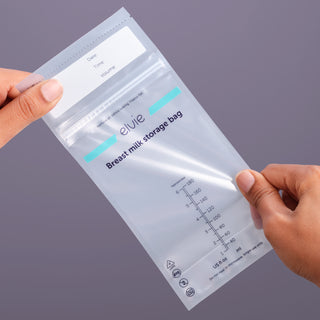 Elvie breast milk storage bag held by two hands against a grey background