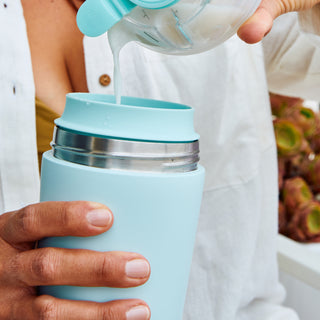 Person pouring breast milk from a breast pump into an Elvie breast milk cooler.