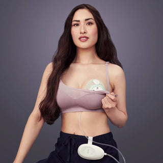 Woman wearing a Elvie Stride single breast pump in bra against a grey background