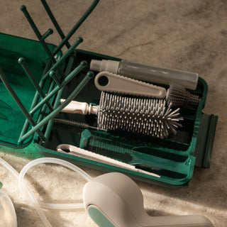 Set of breast pump cleaning brushes in a green case on a concrete surface