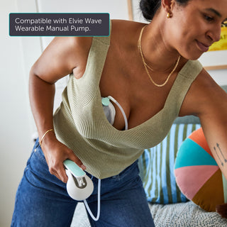 Woman using an Elvie Wave wearable manual pump with text indicating tubing compatibility with Elvie Wave.